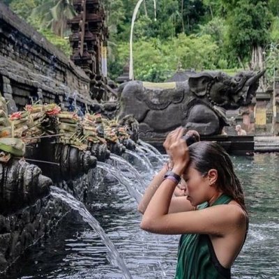 Tirta Empul, a sacred Hindu temple in Bali, featuring holy spring water pools where visitors participate in traditional purification rituals, surrounded by lush greenery and stone carvings.