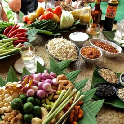 Guests participating in a Balinese cooking class, preparing traditional dishes with fresh local ingredients in a tropical kitchen setting.