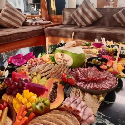 A beautifully arranged grazing platter or floating tray with fresh fruits, snacks, and desserts, served in a villa’s pool or dining area for a luxurious experience