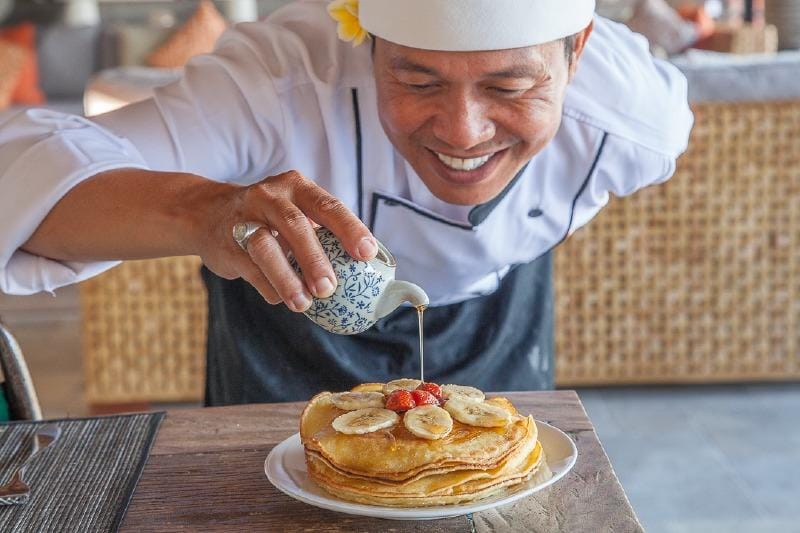 Private chef preparing meals in a family-friendly villa in Bali, with a dining setup in a tropical setting for personalized culinary experiences