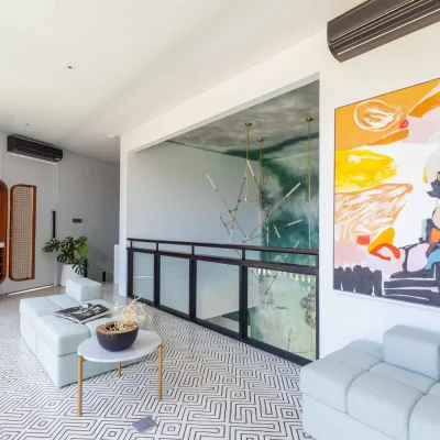 MandalaOasis_Bali_11_SecondLiving_11zon A luxurious tropical villa named Mandala Oasis Villa, featuring an infinity pool surrounded by palm trees, lush gardens, and modern open-air architecture under a bright blue sky.