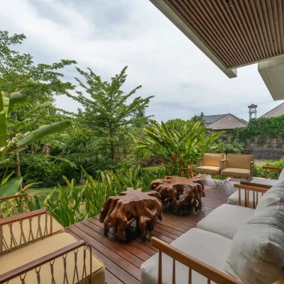Mandala Oasis Villa A luxurious tropical villa named Mandala Oasis Villa, featuring an infinity pool surrounded by palm trees, lush gardens, and modern open-air architecture under a bright blue sky.
